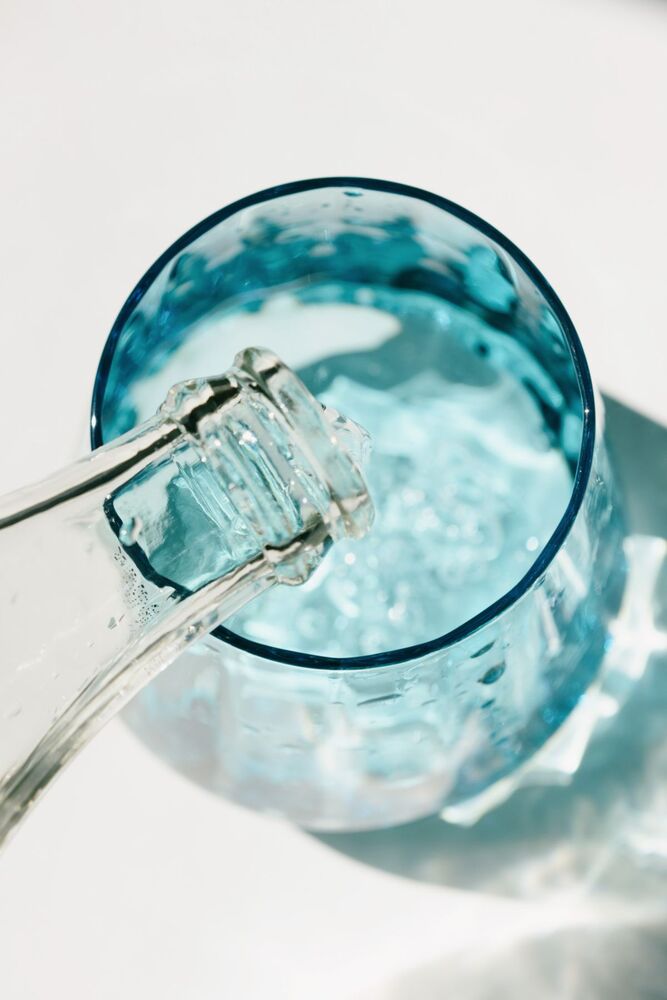 Água limpa sendo servida em um copo azul